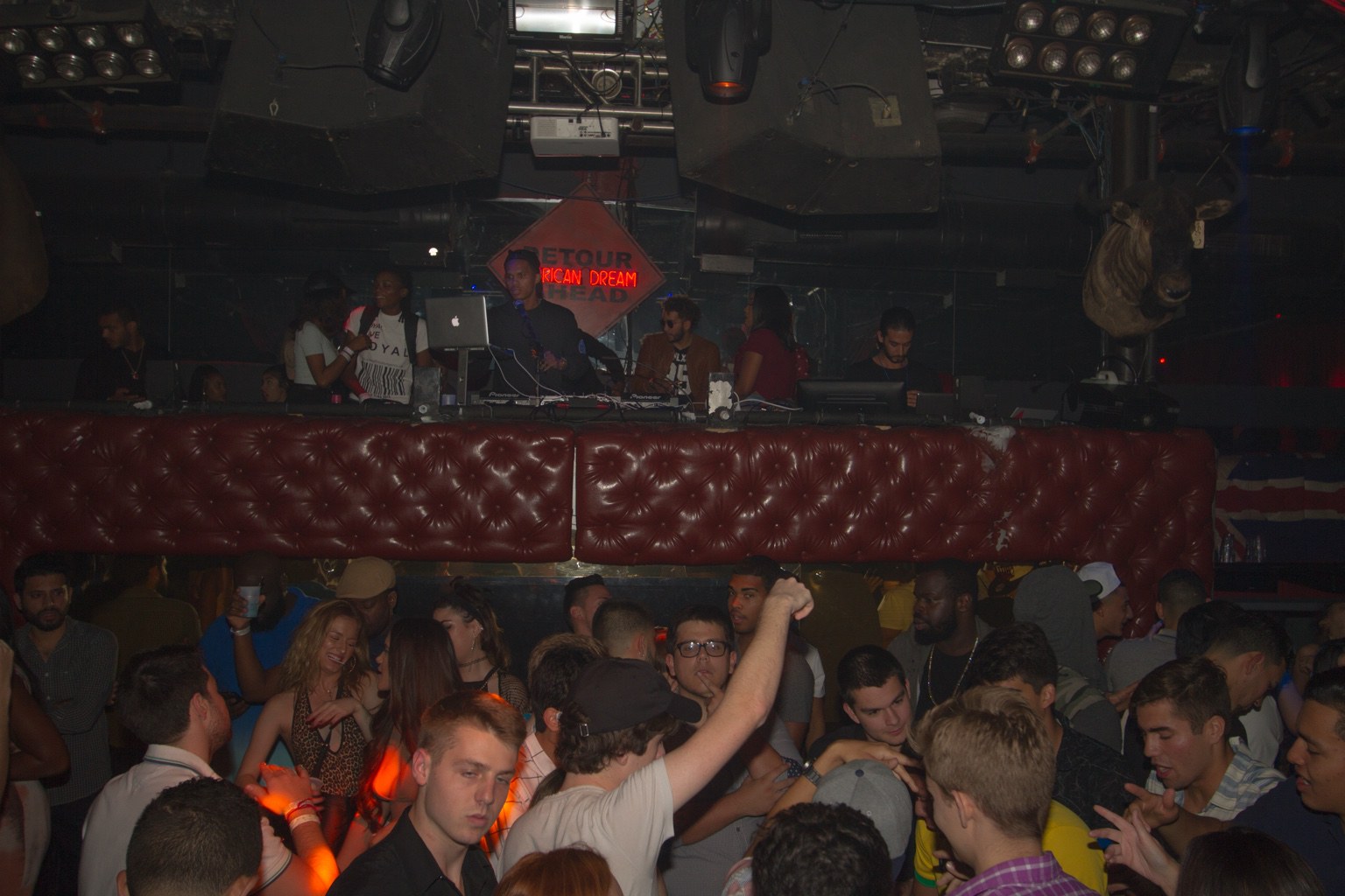 A DJ booth overlooking nightclub guests on the dance floor